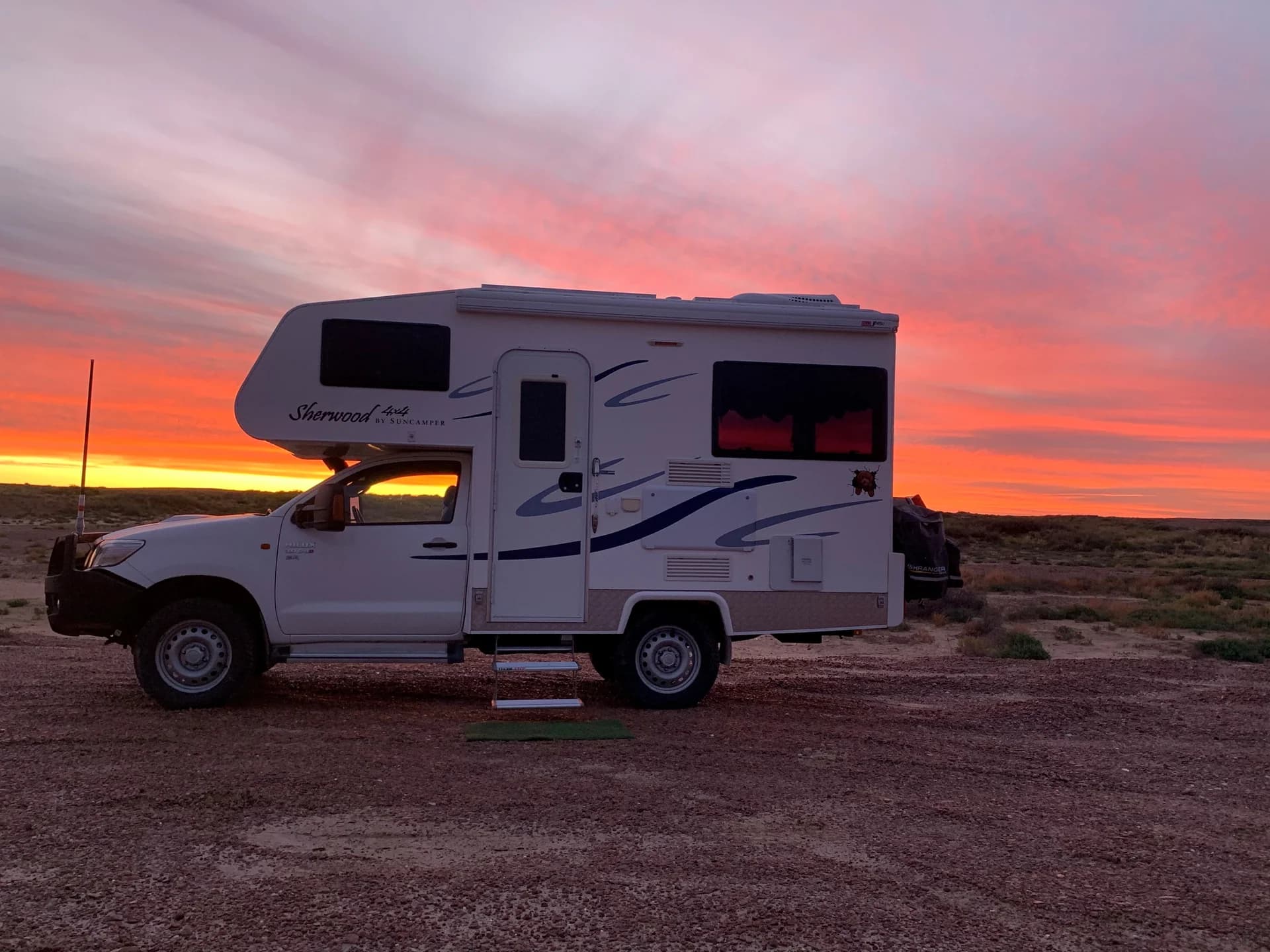 Suncamper motorhome silhouetted at sunset on the shores of Lake Eyre