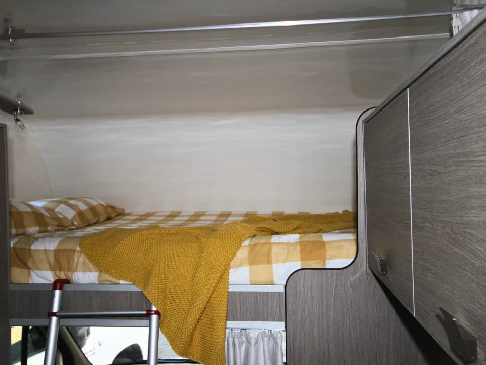 Suncamper Saxby F-2 overhead bunk sleeping area with ladder — sleeping
