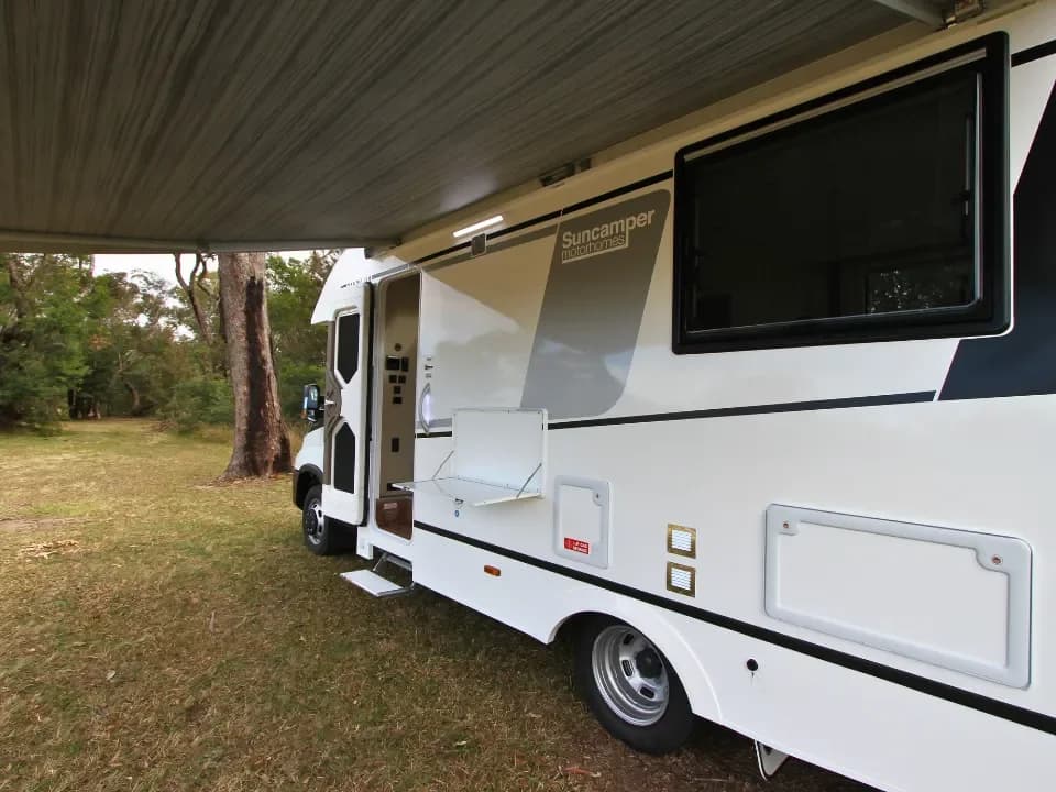 Suncamper Saxby V-2 passenger awning extended with table — exterior