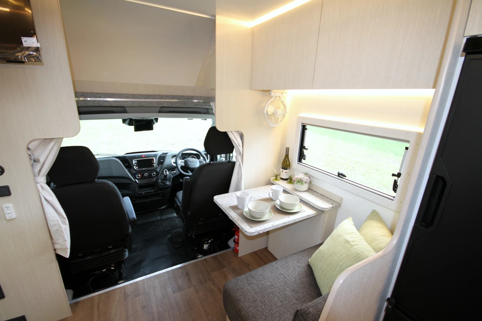 Suncamper Saxby X-2 cafe dinette with table set, looking through to the Iveco cab